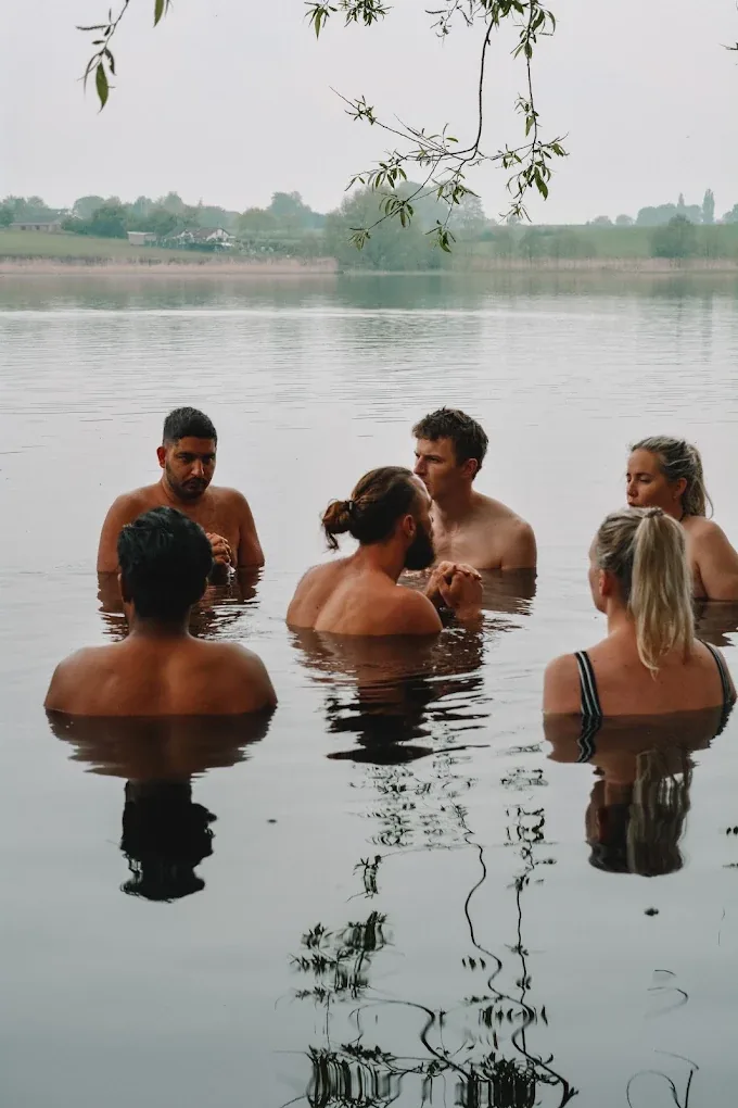 A group standing chest-deep in the lake during a cold-water dip